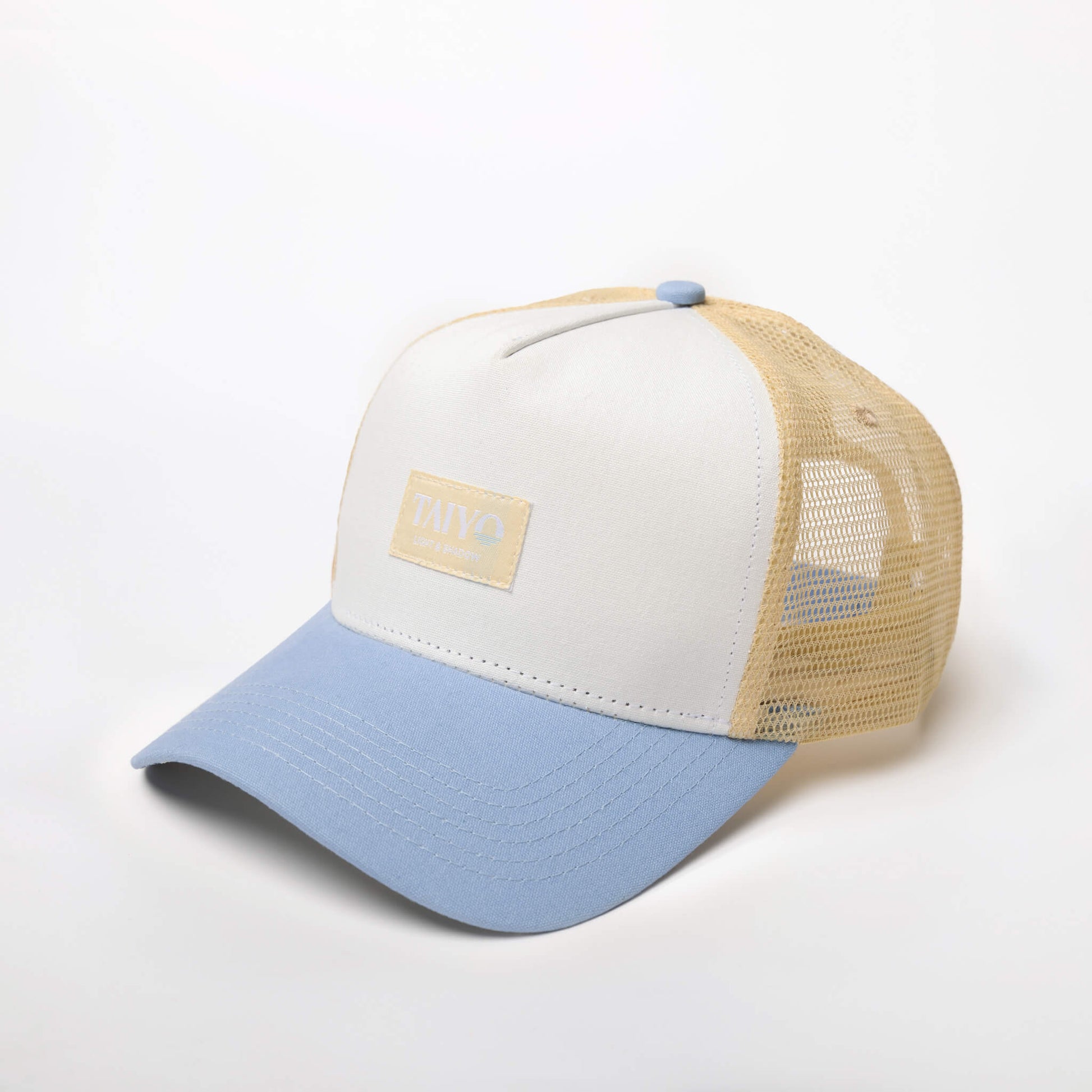 Casquette Ceramic Trucker Blue de TAIYO avec panneau avant blanc cassé, visière bleu ciel, imprimé ceramic sous le visière, patch tissé et mesh beige en polyester recyclé.