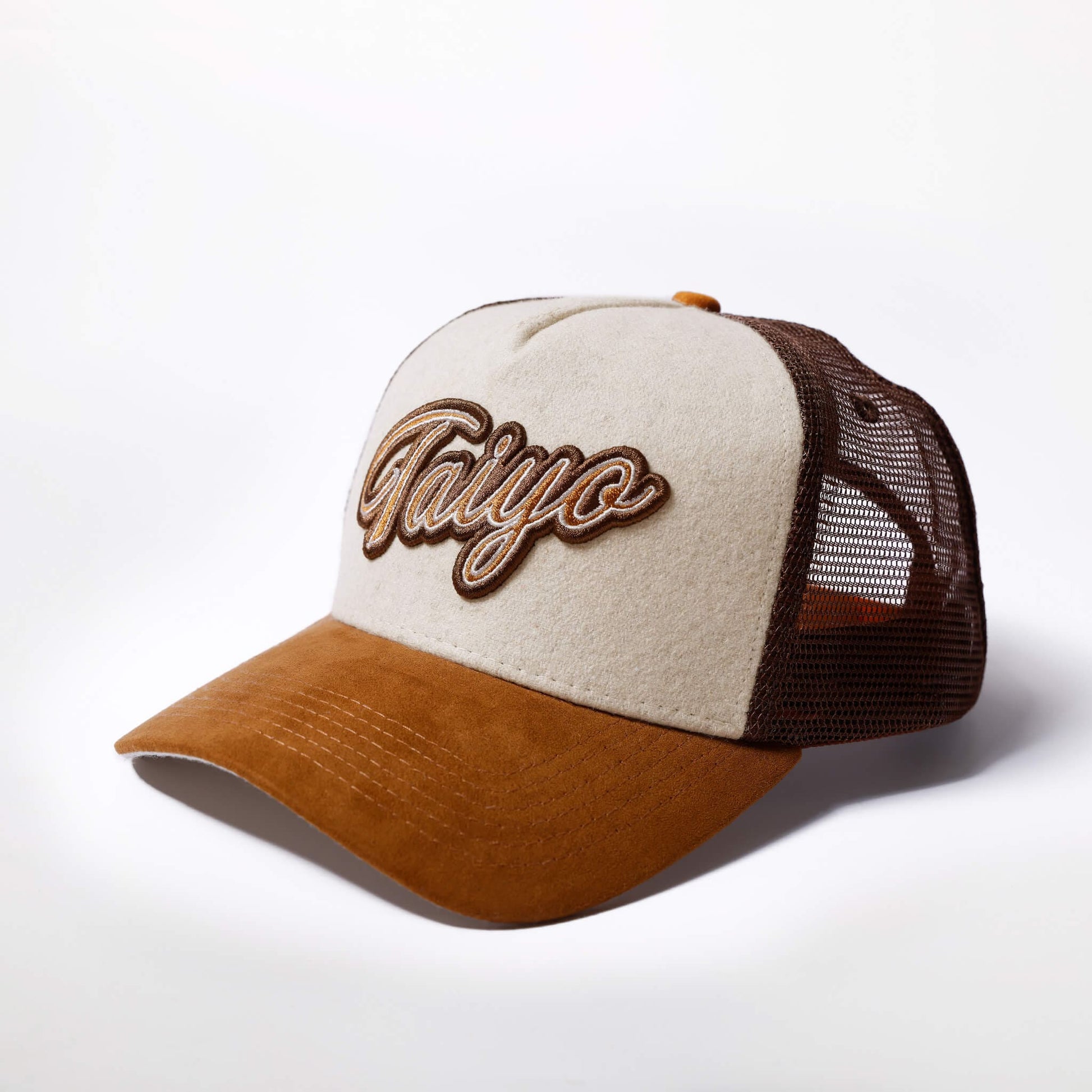 Casquette trucker Taiyo en laine beige avec visière en suede camel et filet marron, logo brodé sur le devant.