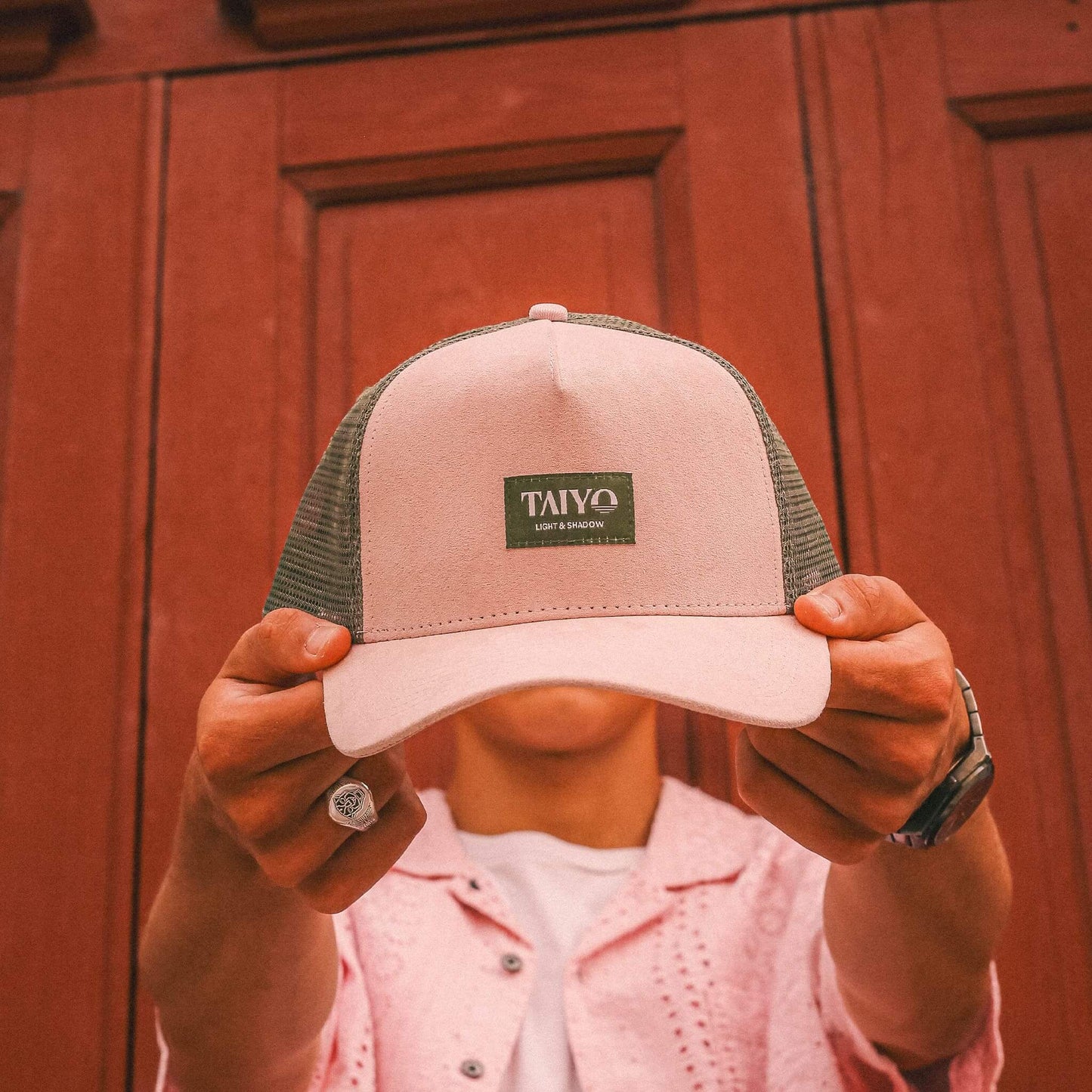 casquette trucker en suede rose et filet vert tenue à deux main