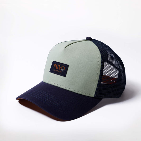 Casquette trucker Taiyo vert clair avec visière bleu marine et filet à l'arrière, logo tissé sur patch frontal.